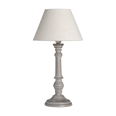 Hill Interiors wooden table lamp with turned column base in a washed beige finish and tapered neutral linen shade, shown on a plain white background.