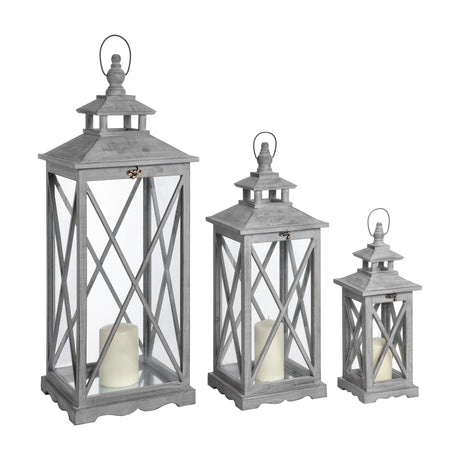 Hill Interiors set of three wooden lanterns in graduated heights, grey finish with cross-section glazed panels and pillar candles, on a white background.
