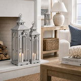 Hill Interiors Wooden Archway Lanterns in grey with lit pillar candles, styled on a hearth beside logs in a coastal living room.