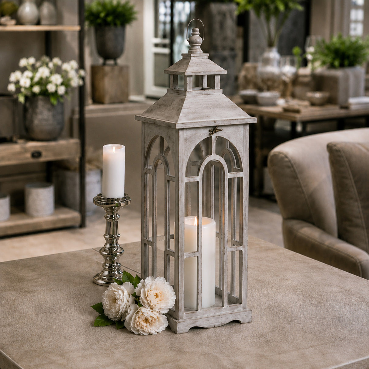 Hill Interiors wooden archway lantern in weathered grey with lit pillar candle, styled on a table with a silver candle holder and white roses.