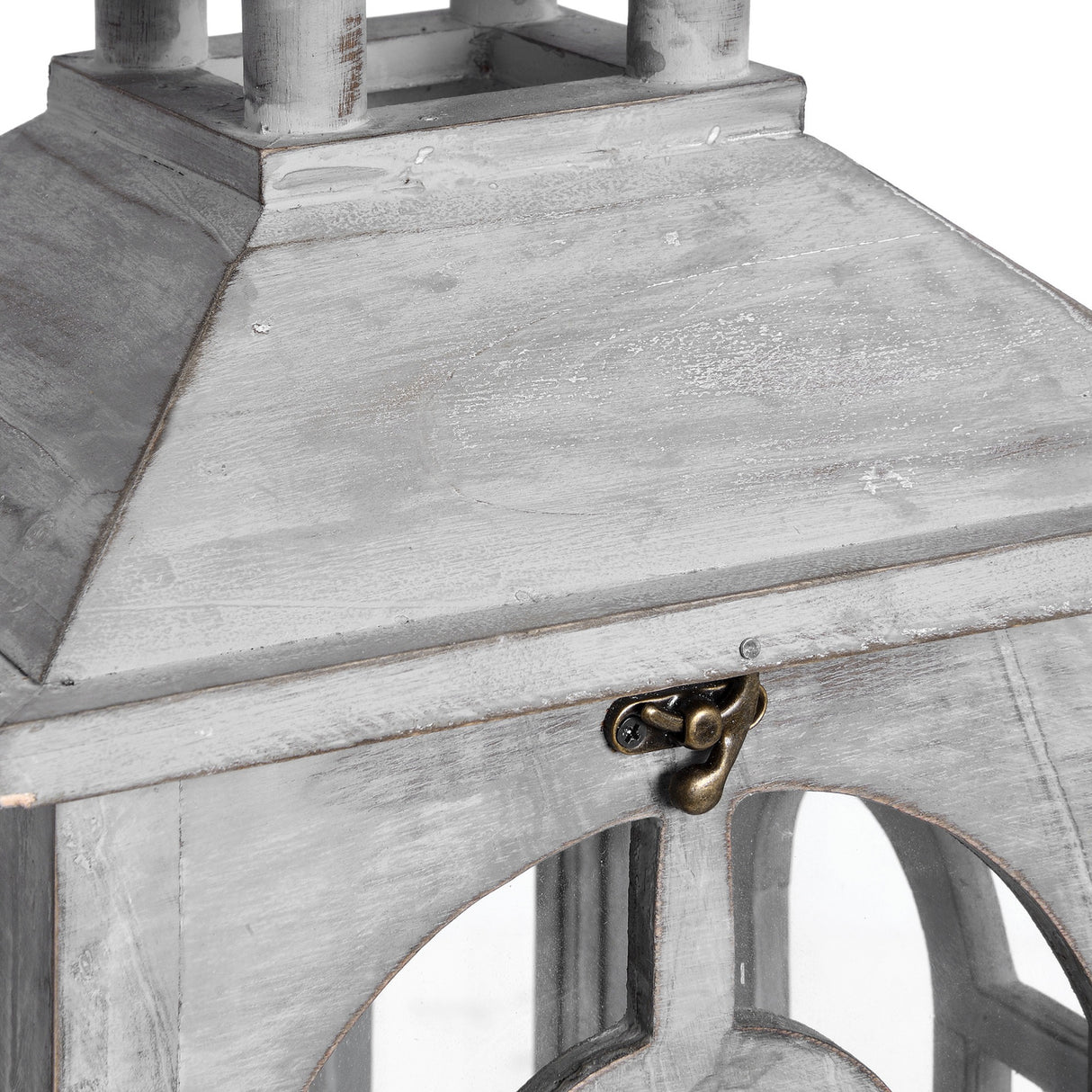 Close-up of the pitched roof and brass latch on a Hill Interiors grey wooden archway lantern, showing the weathered finish and arched opening below.