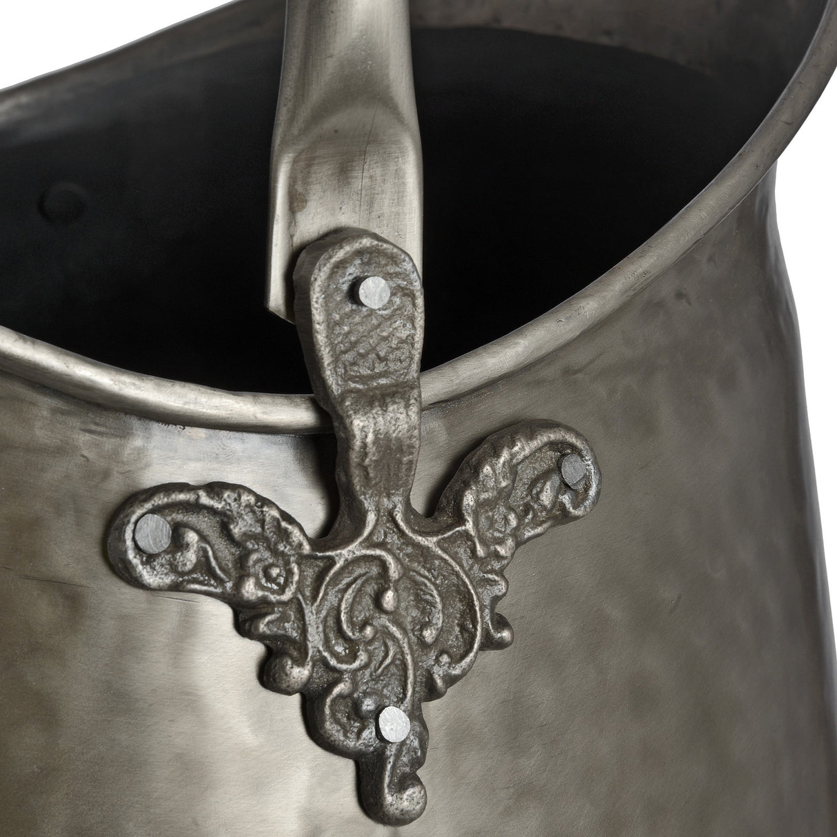 Close-up of Hill Interiors Antique Pewter Coal Bucket in silver, showing the ornate scrollwork handle mount, riveted fixing and swing handle.