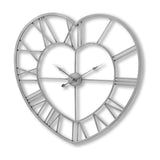 Hill Interiors Skeleton Heart Wall Clock in silver metal, with openwork heart-shaped frame, Roman numerals and exposed hands on a white background.