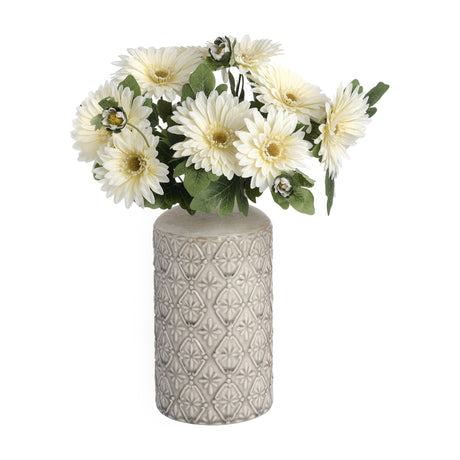Hill Interiors white embossed cylinder vase with textured floral relief, holding cream gerbera daisies and green foliage against a white background.