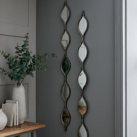 Hill Interiors Undulating Panel silver wall mirrors, two tall slim pieces with wavy teardrop segments, mounted above a console with eucalyptus.