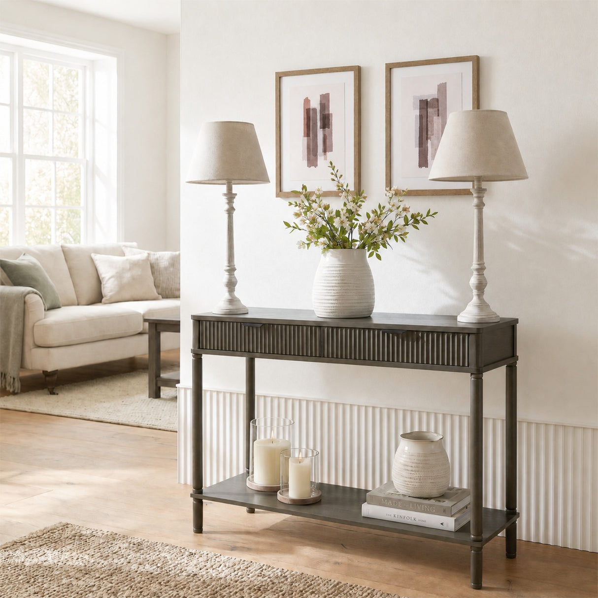 Pair of Hill Interiors Wooden Table Lamps in grey with turned bases and tapered shades on a dark console styled with a vase in a bright living room.