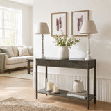 Pair of Hill Interiors Wooden Table Lamps in grey with turned bases and tapered shades on a dark console styled with a vase in a bright living room.