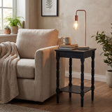 Hill Interiors copper industrial table lamp with exposed bulb and stone base on a black turned-leg side table beside a beige armchair in a living room.