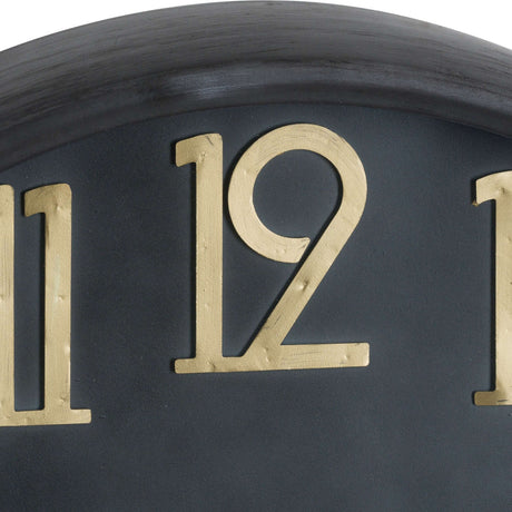 Close-up of the Hill Interiors Large Brass and Black Round Wall Clock showing brass numerals 11 and 12 on the black dial beneath the curved brass frame.
