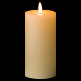 Hill Interiors LED pillar candle in cream wax effect with a lit flame-shaped glow, 15cm tall, shown against a black background.