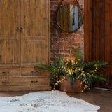 Hill Interiors 100 LED battery micro string lights on silver wire glowing warm white across ferns in a copper planter beside a rustic wood wardrobe.