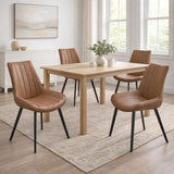 Four Hill Interiors Draxinby brown faux-leather dining chairs with black legs around a light oak table in a bright dining room with framed art.