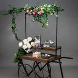 Hill Interiors 200cm faux ivy garland draped over a wooden cart with pink and cream faux roses, glass sweet jars and silver bird ornaments.