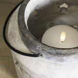 Close-up of Hill Interiors Large Stone Star Lantern ceramic candle holder in beige with stone-effect finish, black wire handle and lit pillar candle inside.