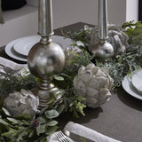 Hill Interiors white resin artichoke ornaments styled along a festive table runner with silver candlesticks, frosted greenery and white plates.