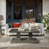 Hill Interiors medium white resin artichoke ornament on a dark wood coffee table with books and a stone vase in a sunlit living room.