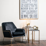 Hill Interiors Set of 2 Gold and Black Marble-Effect Side Tables styled beside a navy velvet armchair with a glass dome lamp and framed wall art.