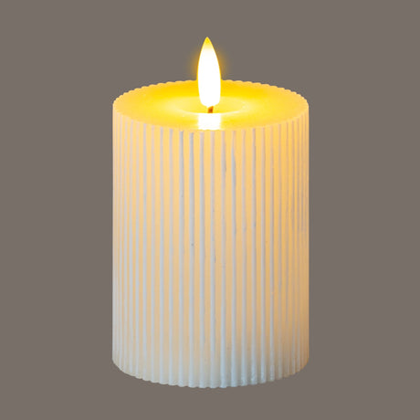 Hill Interiors Textured Ribbed LED Pillar Candle in beige with vertical ribbed plastic body and glowing flame-effect tip on a grey background.