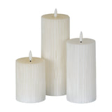 Hill Interiors Textured Ribbed LED Pillar Candles in beige, shown as a trio of ribbed plastic pillars at varying heights with LED flame tips, on white.