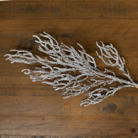 Hill Interiors Snow Covered Branch in white plastic with frosted snow-effect finish, laid across a rustic wooden plank surface.