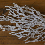 Hill Interiors Snow Covered Branch in white plastic with slender twigs dusted in snow effect finish, laid on a warm wooden surface.