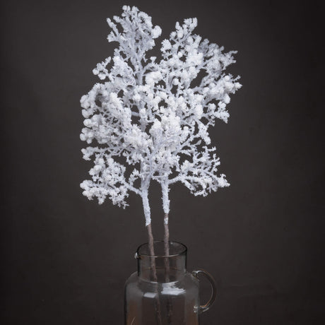 Hill Interiors Snowy Faux Branch 110cm with frosted white moulded plastic twigs displayed upright in a clear glass jug against a dark background.