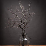 Hill Interiors Large Faux Branch Spray with bare twig-like brown plastic stems, displayed in a clear glass jug against a dark grey background.