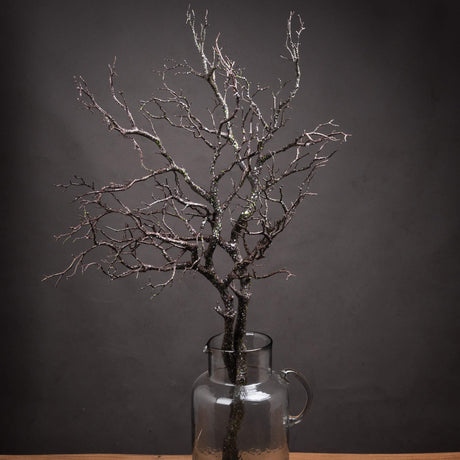 Hill Interiors Large Faux Branch Spray with bare twig-like brown plastic stems, displayed in a clear glass jug against a dark grey background.