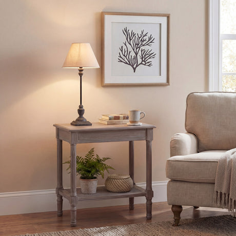 Hill Interiors Ondelle Stem Table Lamp in brown metal with a tapered shade, styled on a wooden side table beside a cream armchair and framed coral print.
