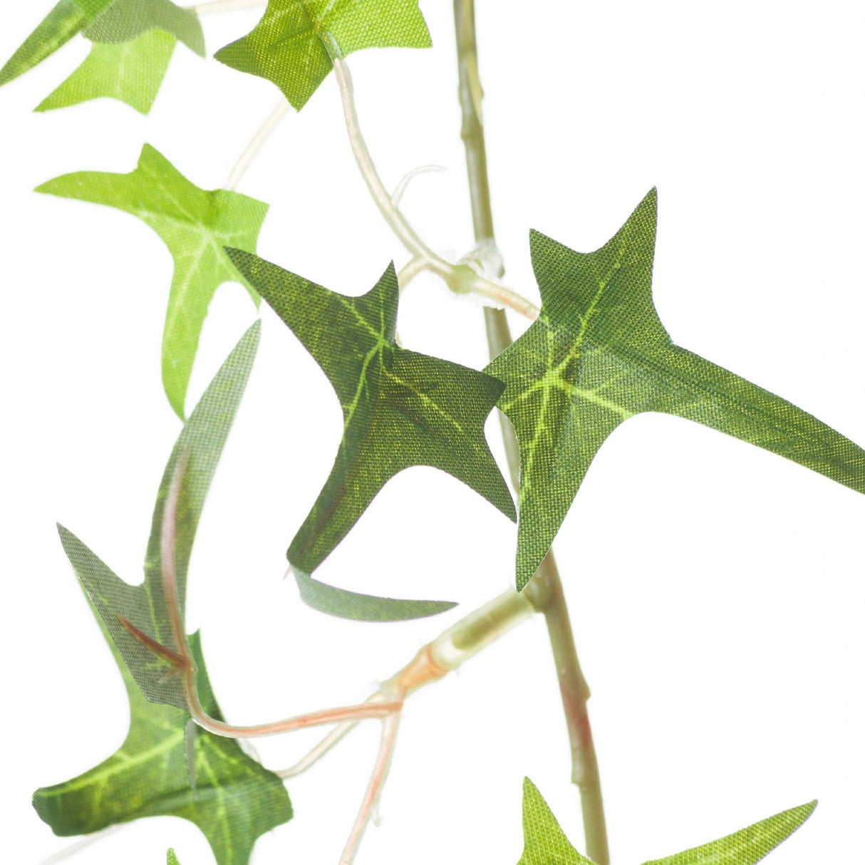Close-up of Hill Interiors Small Faux Ivy Garland showing pointed green plastic leaves and slim flexible stems against a plain white background.