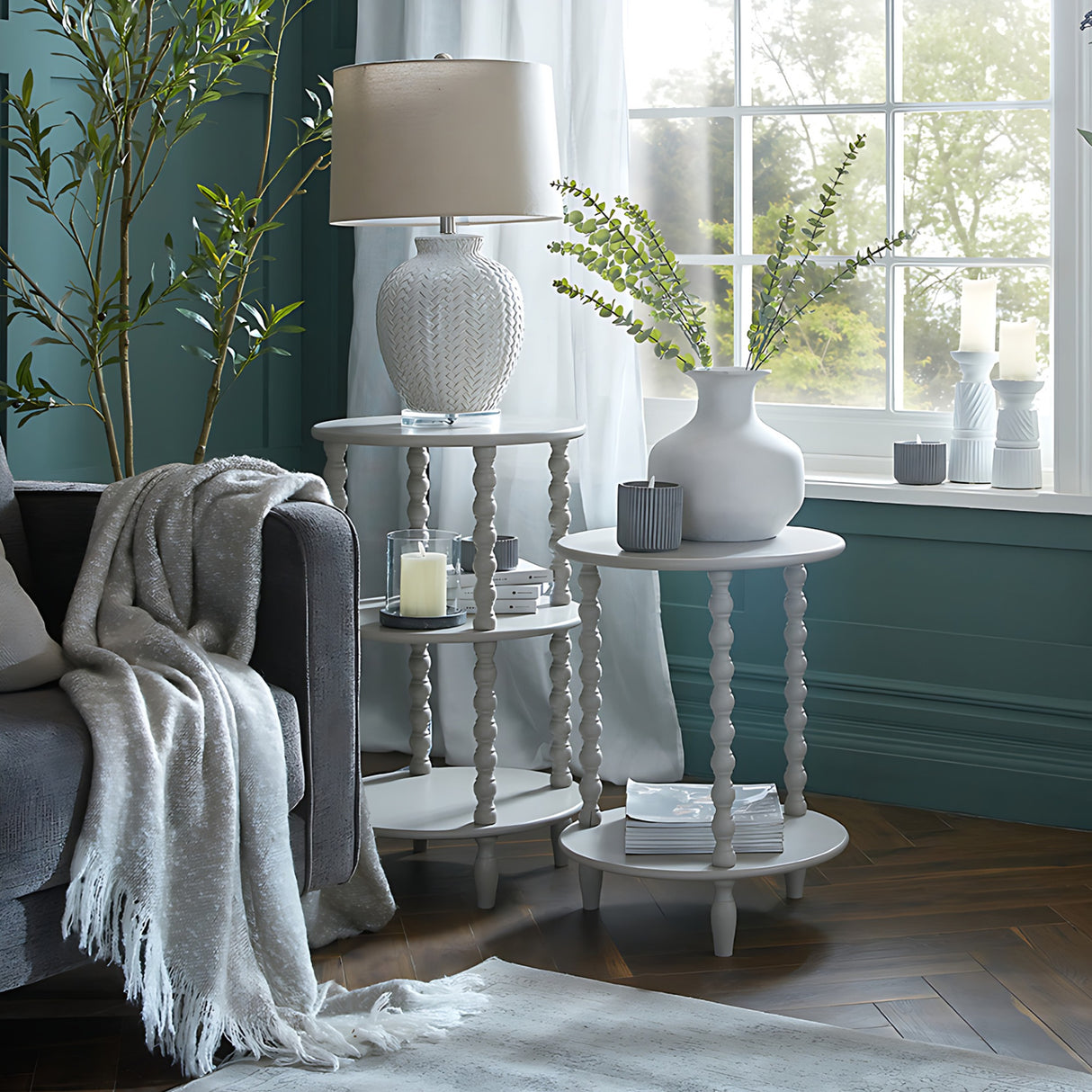 Hill Interiors Squat Stone Ceramic Vase in beige with eucalyptus stems, styled on a white turned-leg side table by a sunlit living room window.