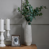 Hill Interiors Large Tall Ceramic Vase in beige holding eucalyptus stems on a wooden console beside white candle holders and a framed print.