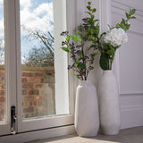 Hill Interiors Tall Ceramic Vase in beige with white hydrangea and berry stems, paired with a smaller vase on a sunlit window sill.