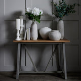 Hill Interiors Tall Ceramic Vase in beige with white hydrangeas, styled on a wooden console table with candles, books and neutral vases against grey panelling.