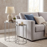 Hill Interiors Quatrefoil mirrored set of two nesting side tables in silver metal, styled beside a grey sofa with a lamp, books and candle on top.