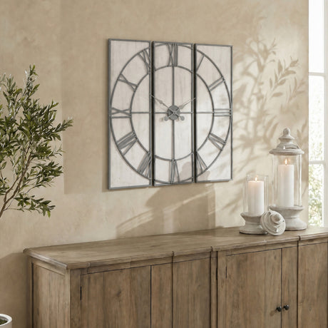 Hill Interiors Panelled Metal Wall Clock in silver, large square three-panel design with open Roman numeral dial, mounted above a wooden sideboard.