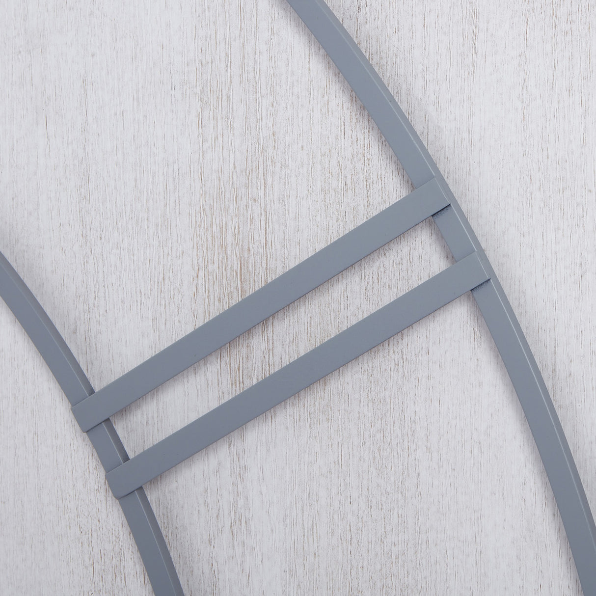 Close-up of the Hill Interiors Panelled Metal Wall Clock in silver, showing the panelled metal frame bars against a pale wood background.