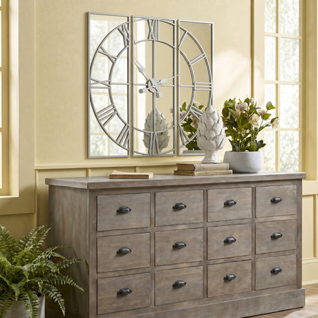 Hill Interiors mirrored round wall clock in silver with Roman numerals, displayed above a wooden sideboard in a neutral living room setting.