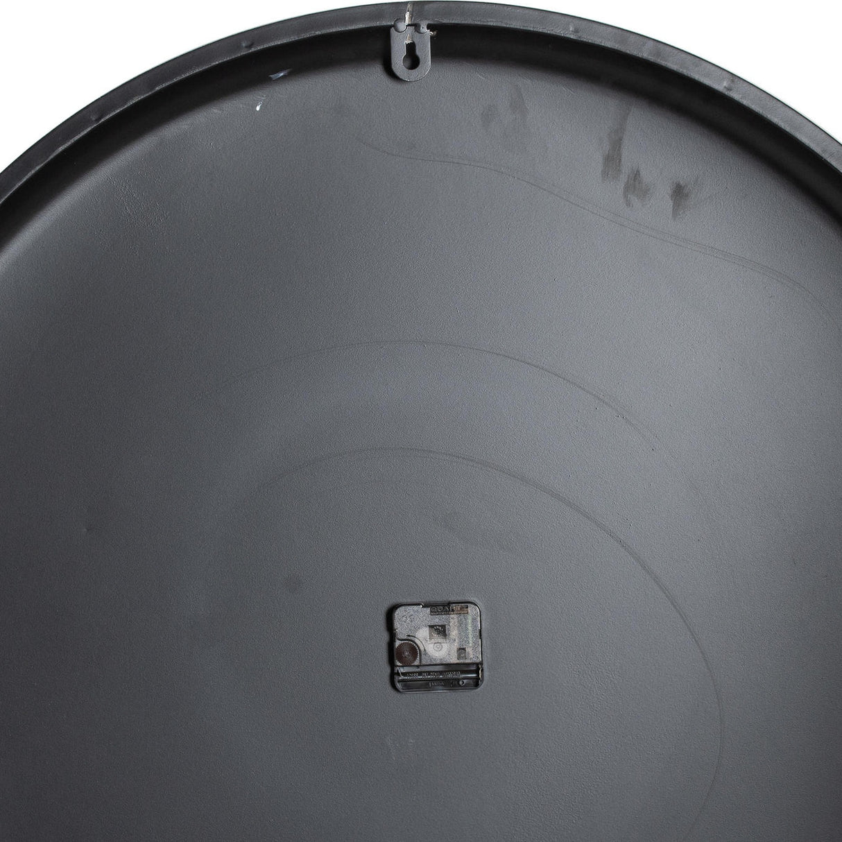 Rear view of the Hill Interiors Large Round Metal Wall Clock in grey, showing the concave metal back with central quartz movement and top hanging hook.