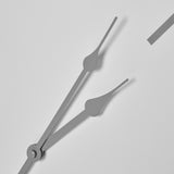 Close-up of Hill Interiors Round Metal Wall Clock in white, showing slender grey hour and minute hands meeting at the central spindle with a numeral edge.