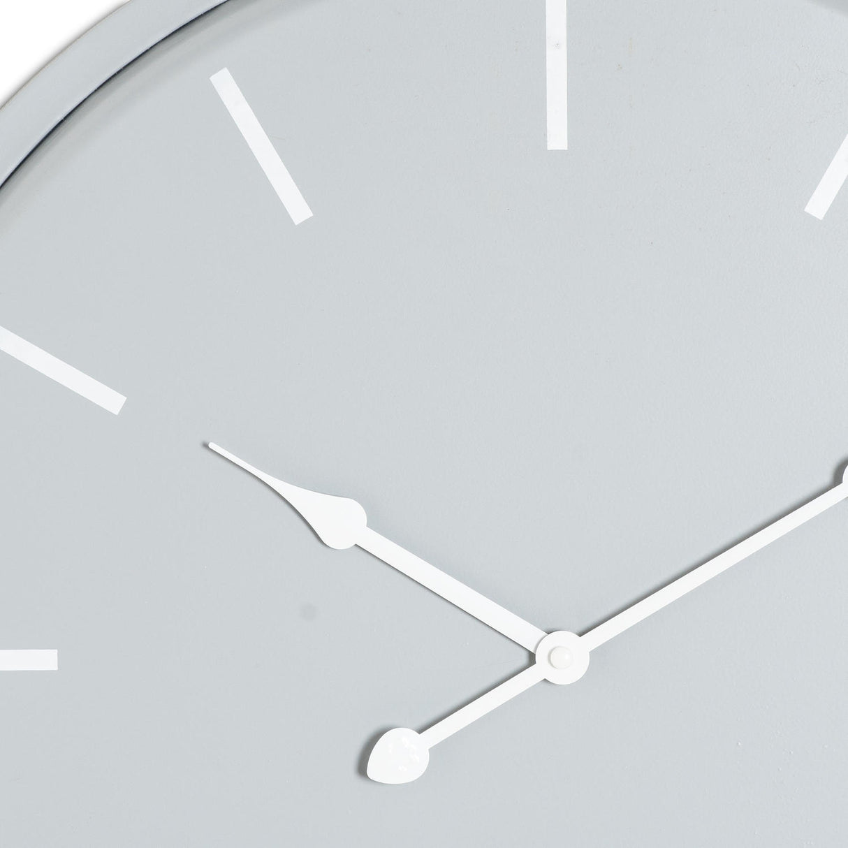Close-up of the Hill Interiors Round Metal Wall Clock in grey, showing white baton markers and slim white hour and minute hands on a soft grey dial.
