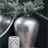 Hill Interiors Silver Astral Vase with rounded ceramic body and silver glaze, holding eucalyptus stems beside a round mirror and lattice candle holder.