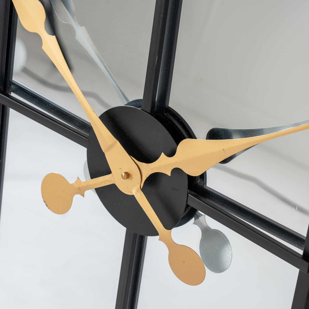 Close-up of Hill Interiors Black and Gold Round Wall Clock 113cm showing central black hub with ornate gold hour and minute hands over glass face.