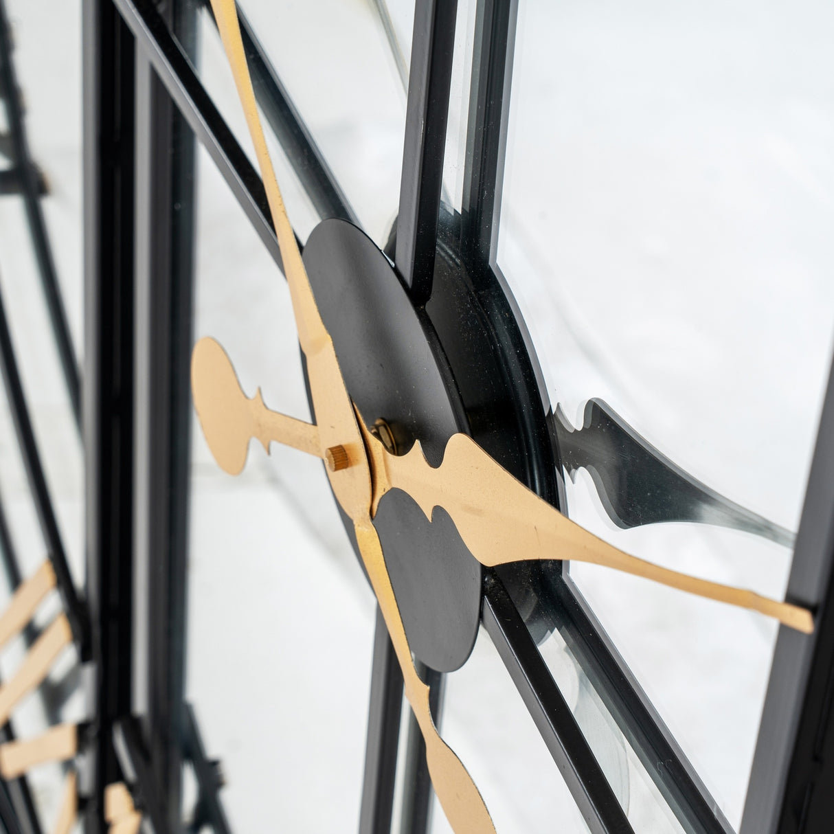 Close-up of Hill Interiors Black and Gold Round Wall Clock 113cm showing gold hands, black centre disc and metal frame against a light background.