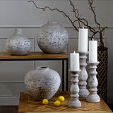 Hill Interiors Stone Ceramic Vases in beige with speckled matt finish, grouped with matching candlesticks and lit pillar candles on wooden console tables.