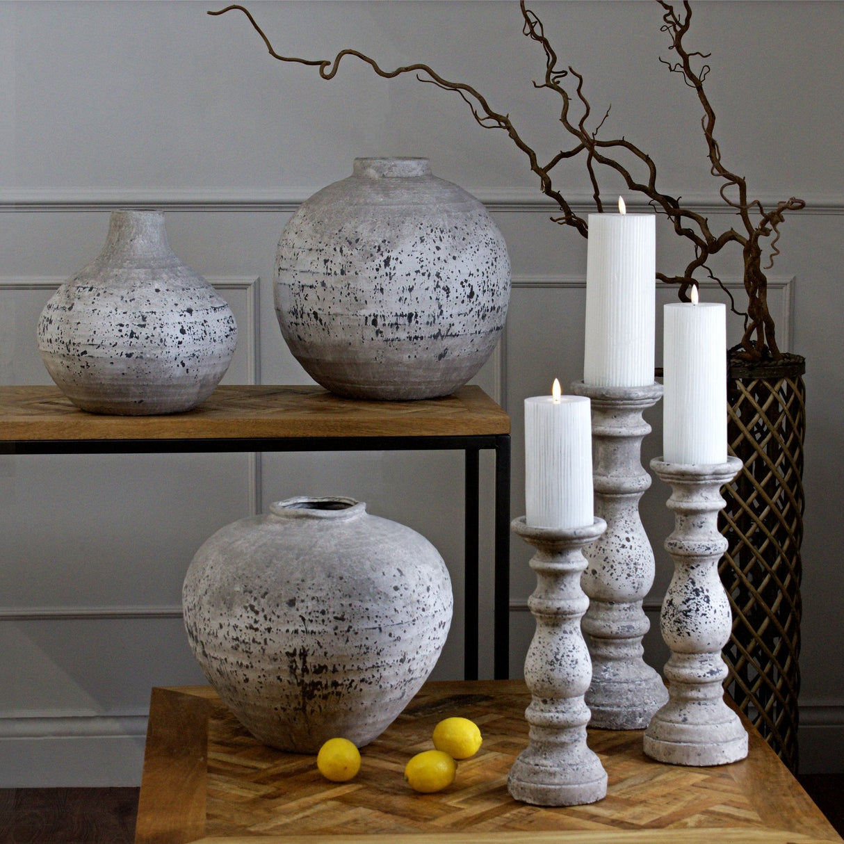 Hill Interiors Large Stone Ceramic Vase in beige with textured stone-effect finish, styled on a wooden table with candlesticks, lemons and vases.