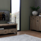 Hill Interiors Large Stone Ceramic Column Candle Holders in beige, paired on books beside a window, styled with a wooden TV unit and sideboard.