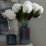 Hill Interiors Large Indigo Scalloped Ceramic Vase in blue holding white hydrangea stems, styled on a console beside a smaller ridged pot and abstract artwork.