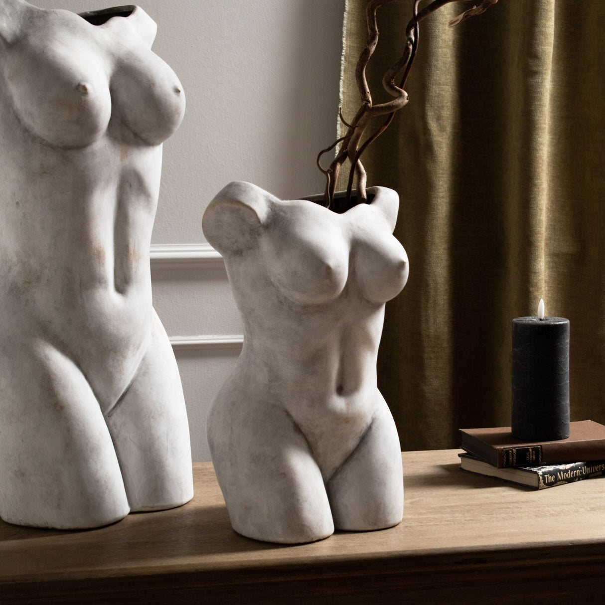 Hill Interiors Female Figure Ceramic Vase in beige displayed on a wooden sideboard with a taller companion vase, books and a black pillar candle.