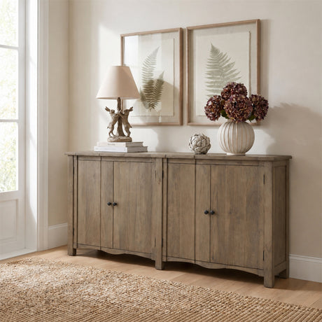 Hill Interiors wooden four-door sideboard in warm brown, styled in a neutral room with a lamp, vase and framed fern prints above.